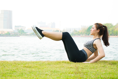 Asian sport woman warm up to exercise on green lawns on water background for healthの写真素材