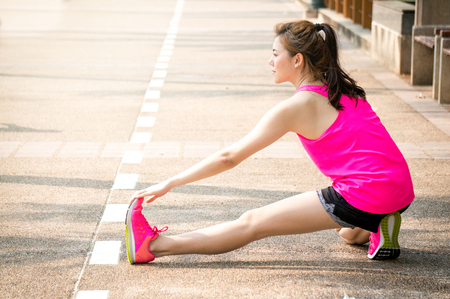 Asian woman warm up for running and yoga in park on building backgroundの写真素材
