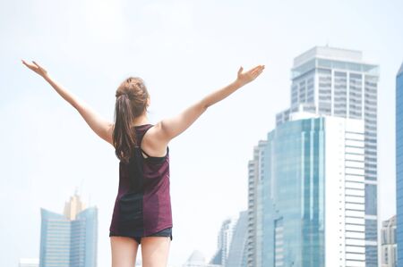Asian sport woman feeling fresh and freedom in park located in center of city on building backgroundの写真素材