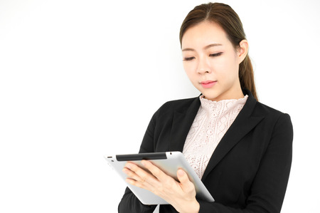 Asian beauty business woman in formal suit holding taplet on white backgroundの写真素材