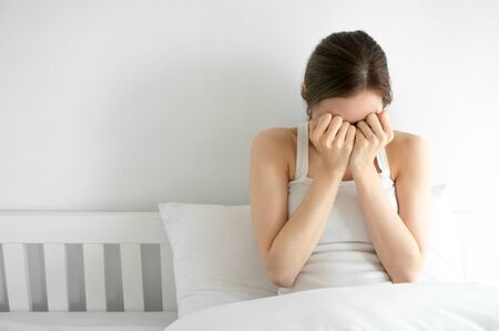 Asian beauty woman is crying on white bedroom in morningの写真素材