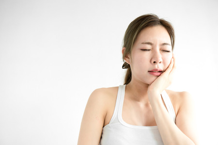 Asian beauty woman have a toothache on white bed in white bedroom in morningの写真素材