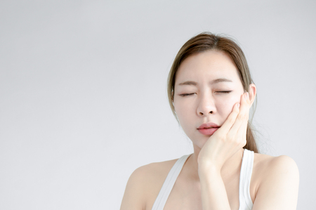 Asian beauty woman have a toothache on white bed in white bedroom in morningの写真素材