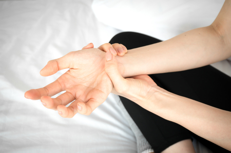 Asian beauty woman have a wrist ache in white bedroomの写真素材