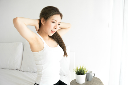 Asian beauty woman wake up and stretching in white bedroom on morningの写真素材