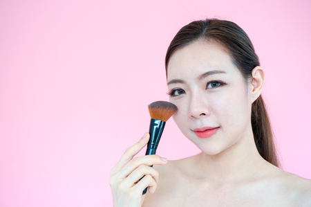Asian beauty woman with blush brush present product for face on pink backgroundの写真素材