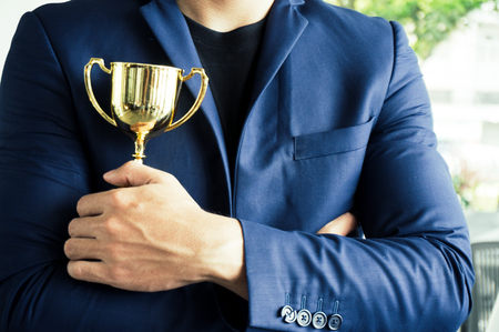 Businessman to be winner holding award trophy with successful and achievementの写真素材