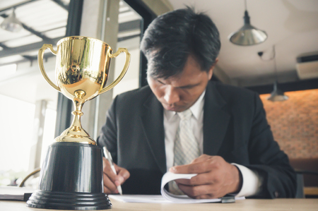 Businessman with colleagues achieve target and successful showing award trophyの写真素材