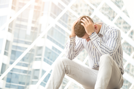 Businessman feeling stress and headache in city outdoorの写真素材