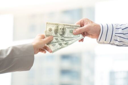 Businessman pay salary to employee in city on building backgroundの写真素材