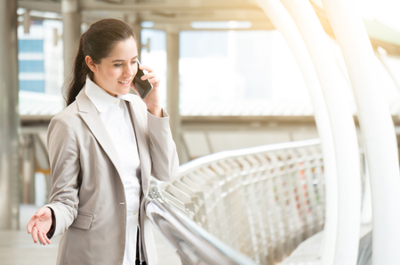 Business woman chatting via phone in hand on building background in cityの写真素材
