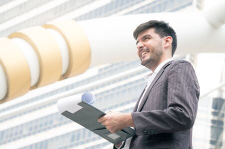 Businessman thinking on building background in city outdoorの写真素材