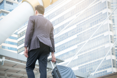 Businessman drag baggage in city on building backgroundの写真素材