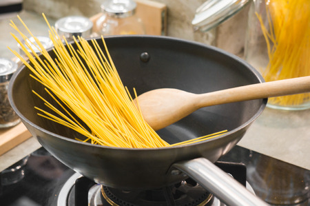 Raw spaghetti in pan ready for cooking in kitchen by chefの写真素材
