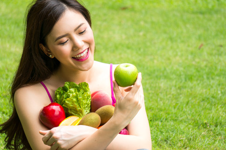 Asian beauty woman hold fruit and vegetable for healthy on grass with smileの写真素材