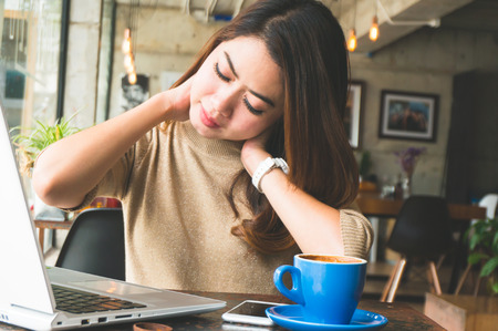 Asian woman have neckache during working with laptop in officeの写真素材