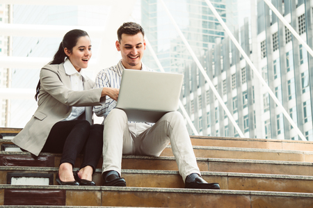 Businessman and woman discuss with smiling and laptop outdoor in cityの写真素材