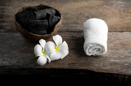 charcoal in coconut shell for spa on the wood background with white towel and flower on banana leaf for advertisementの写真素材