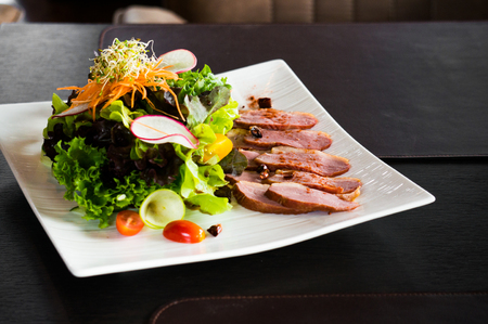 Grilled duck salad on white plate on black table for dinnerの写真素材