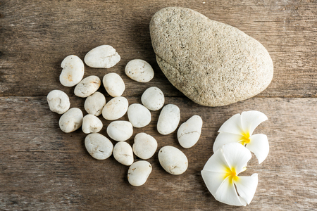White flower and leafs with big and tiny stone and towel on wood table for health spa advertisement and presentationの写真素材