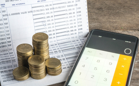 Saving money with gold coin stack and book bank on wood table for investment, business and advertisementの写真素材