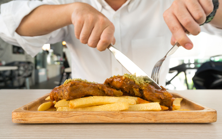 A man wearing white shirt eating steak and french fries in restaurantの写真素材