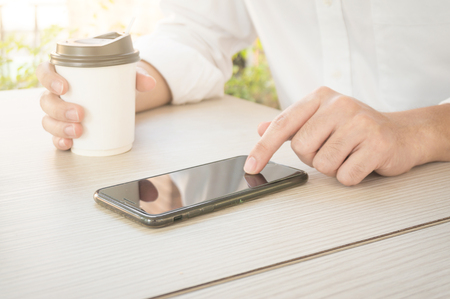 A man is typing phone and holding coffee cupの写真素材