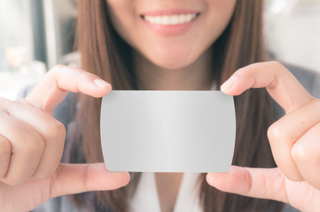 A woman wearing suit with smile is holding credit card in handsの写真素材
