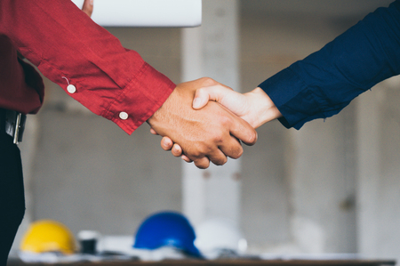 Asian engineer holding blueprint in hand shake hands with colleagueの写真素材