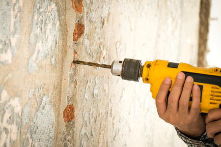 Foreman wearing helmet drilling wal by drillの写真素材