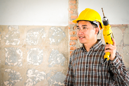 Foreman wearing helmet drilling wal by drillの写真素材