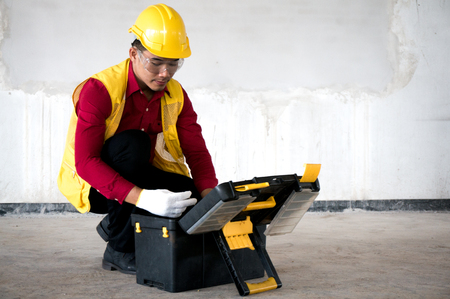 Asian foreman wearing safety helmet with tool box on siteの写真素材