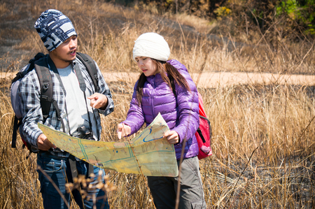 Asian travelers holding map and find target in forestの写真素材
