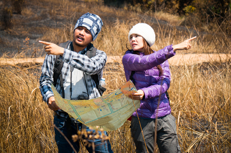 Asian travelers holding map and find target in forestの写真素材