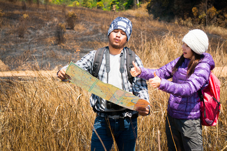 Asian travelers holding map and find target in forestの写真素材