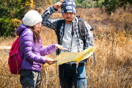Asian travelers holding map and find target in forestの写真素材