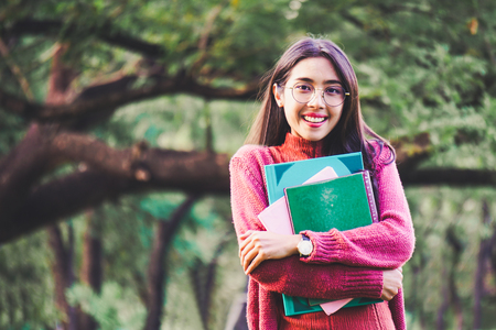 Asian woman with books in park for education conceptの写真素材