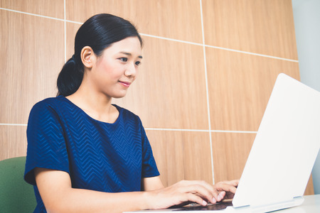 Asian woman working on laptop in officeの写真素材