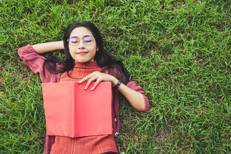 Asian woman feeling relax and cheerful in park with bookの写真素材