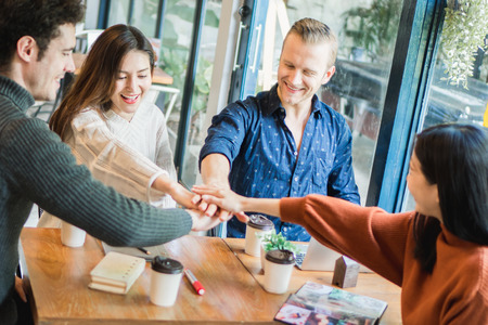 Young businessman and woman meeting in cafÃ© and stack up for new targetの写真素材