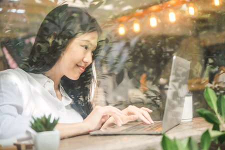 Asian woman working on labtop in coffee shopの写真素材