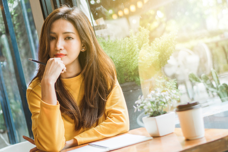 Asian woman working in cafÃ© and write on white paperの写真素材