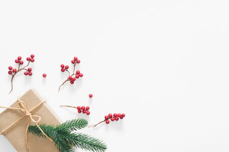 Christmas gift on white background with pine branches, berries and rope. Flat lay, top view, copy spaceの写真素材