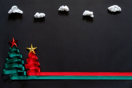Christmas trees made from green and red ribbon with gold star on black background with coppy spaceの写真素材