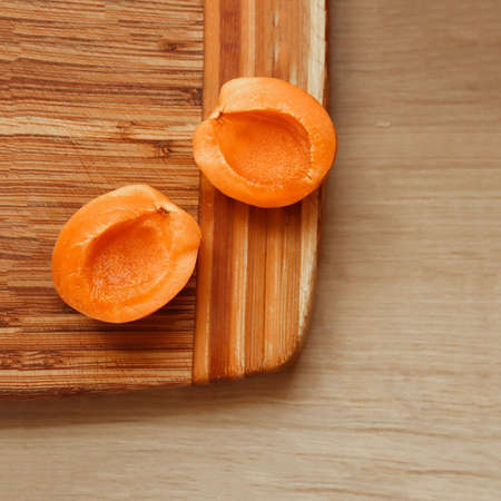Two apricots placed on a wooden desk.の写真素材