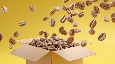 Coffee beans flying out of a cardboard box on yellow backgroundの素材