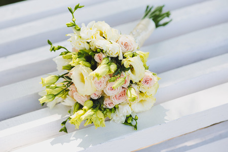 White wedding bouquet of flowers rests on a white benchの写真素材