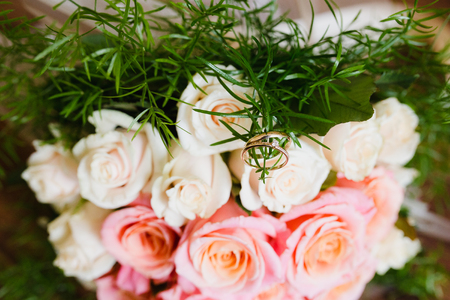 Flowers lie on a wooden table. Flowers closeup. Wedding rings lie on a bouquetの写真素材