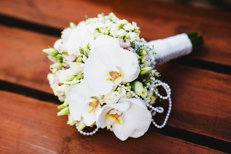 White wedding bouquet of flowers on a green background. Flowers lie on a wooden surfaceの写真素材