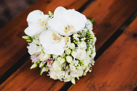 White wedding bouquet of flowers on a green background. Flowers lie on a wooden surfaceの写真素材